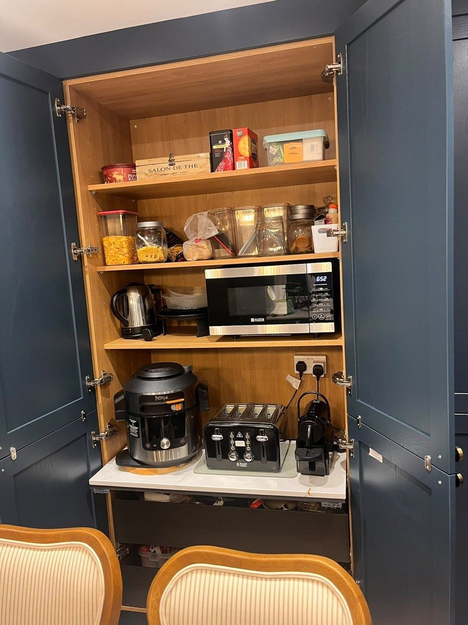 Hartforth Blue tall cupboard opened to show an appliance shelf with toaster, kettle and microwave